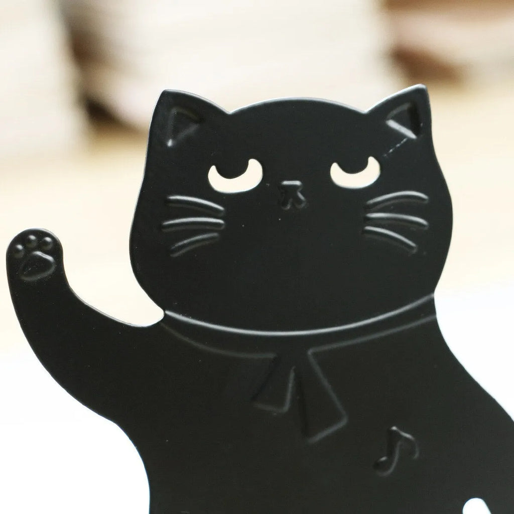 Set of two cartoon cat music themed iron bookends in black and white on a desk holding books upright