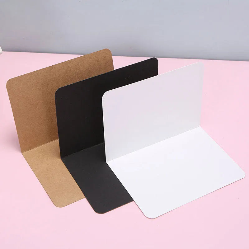 Pack of 100 folded kraft cards in 10x15 cm size, showing black, cowhide, and white colour options.