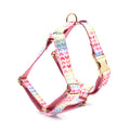 Pink dog harness with a gold buckle and a colourful heart-shaped stone on the chest strap.