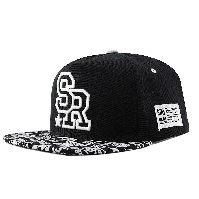 Cotton baseball cap with adjustable strap in black or white, showing embroidered letter detail on the front.