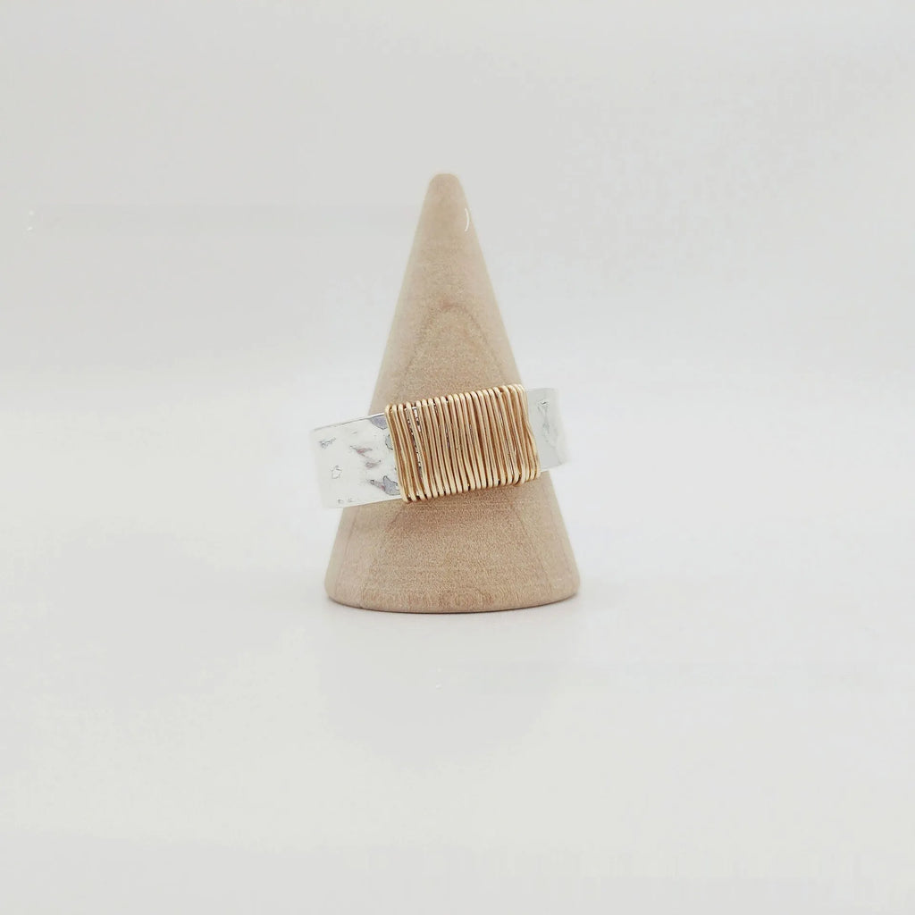 Copper wide face geometric ring bracelet in silver gold coil colour on a plain background.