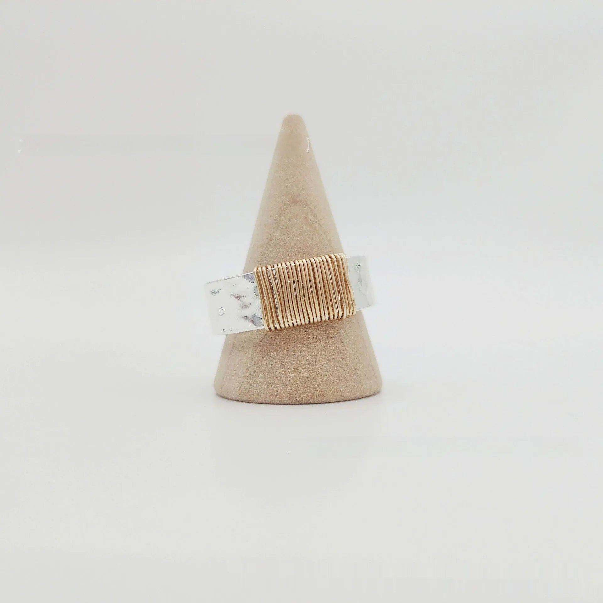 Copper wide face geometric ring bracelet in silver gold coil colour on a plain background.