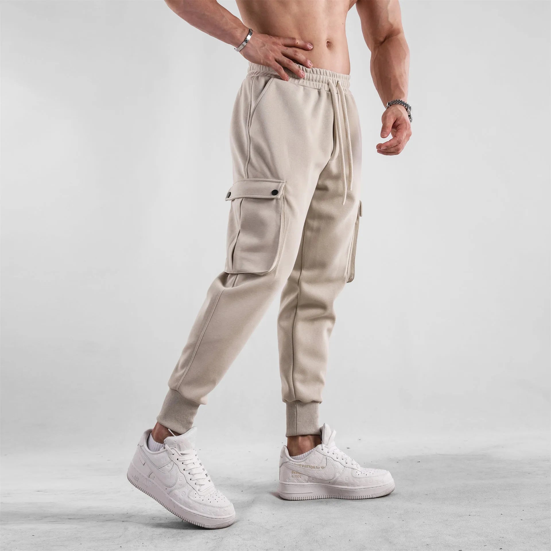 Man wearing loose light grey cotton sports trousers with ankle ties and multiple pockets.