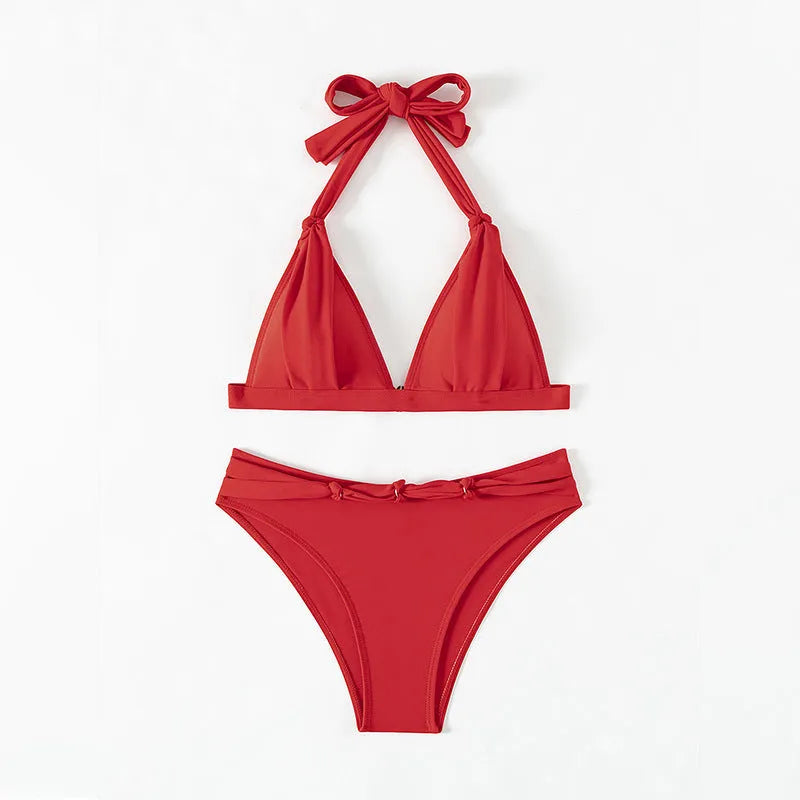Red women's lace-up halterneck bikini with split shorts laid flat.