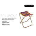 Black ethnic style aluminium alloy folding stool set up on grass.