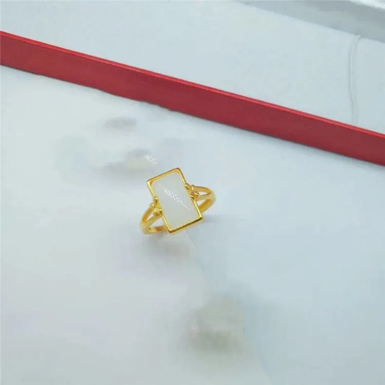 A gold-plated brass ring with an adjustable band and a central green artificial gemstone, in a national style.