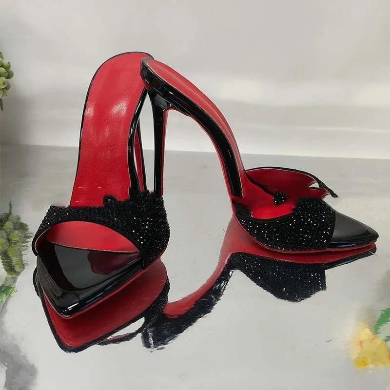 Black rhinestone ankle-strap open toe sandal with super high heel and pointed toe on white background
