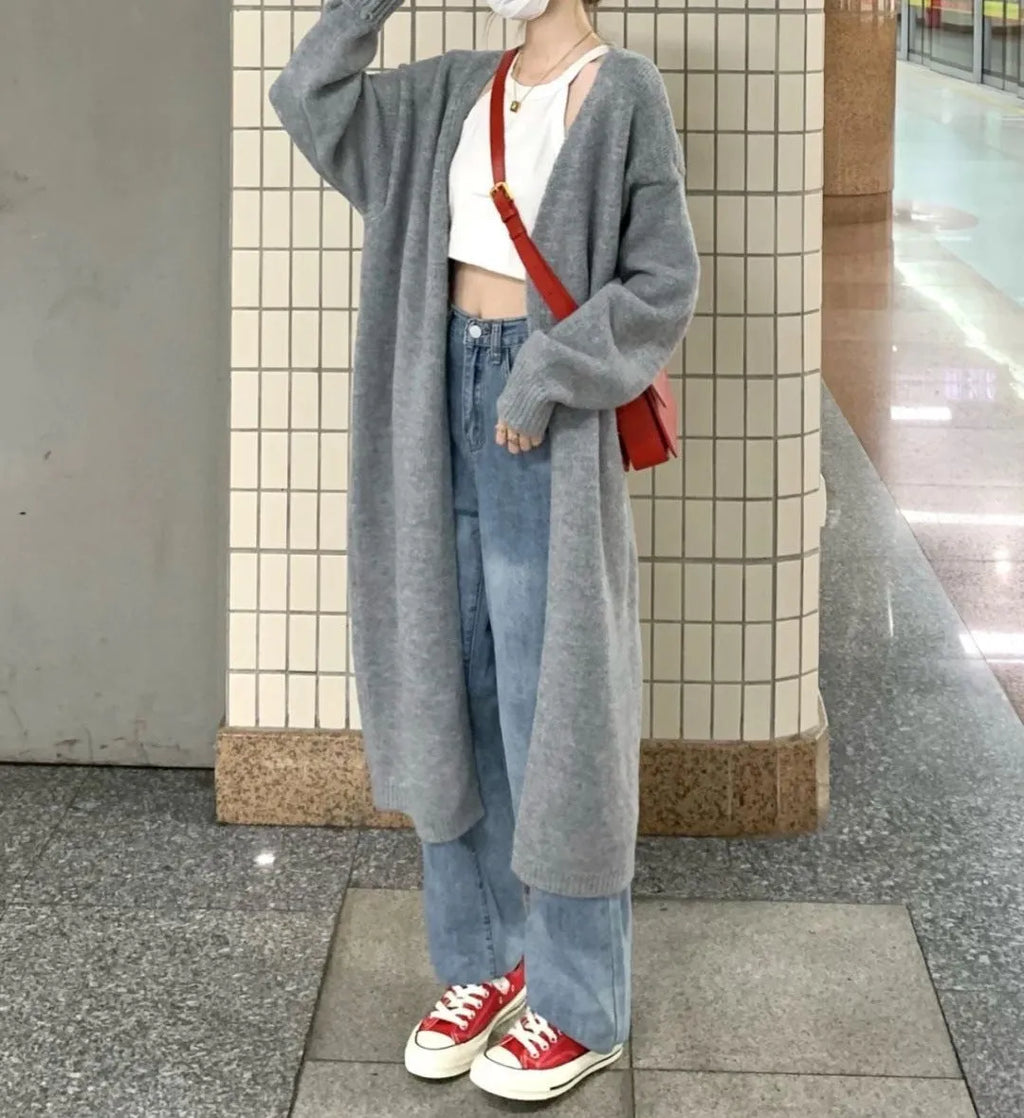 A woman wearing a loose, dark grey knitted chenille cardigan with a 3D-effect texture.
