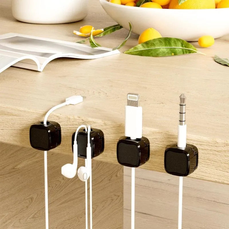 White and black magnetic under-desk cable clips organising various cables with adhesive backing