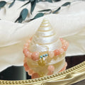 Close-up of a pink natural stone set within a simple silver-toned alloy women's bracelet.