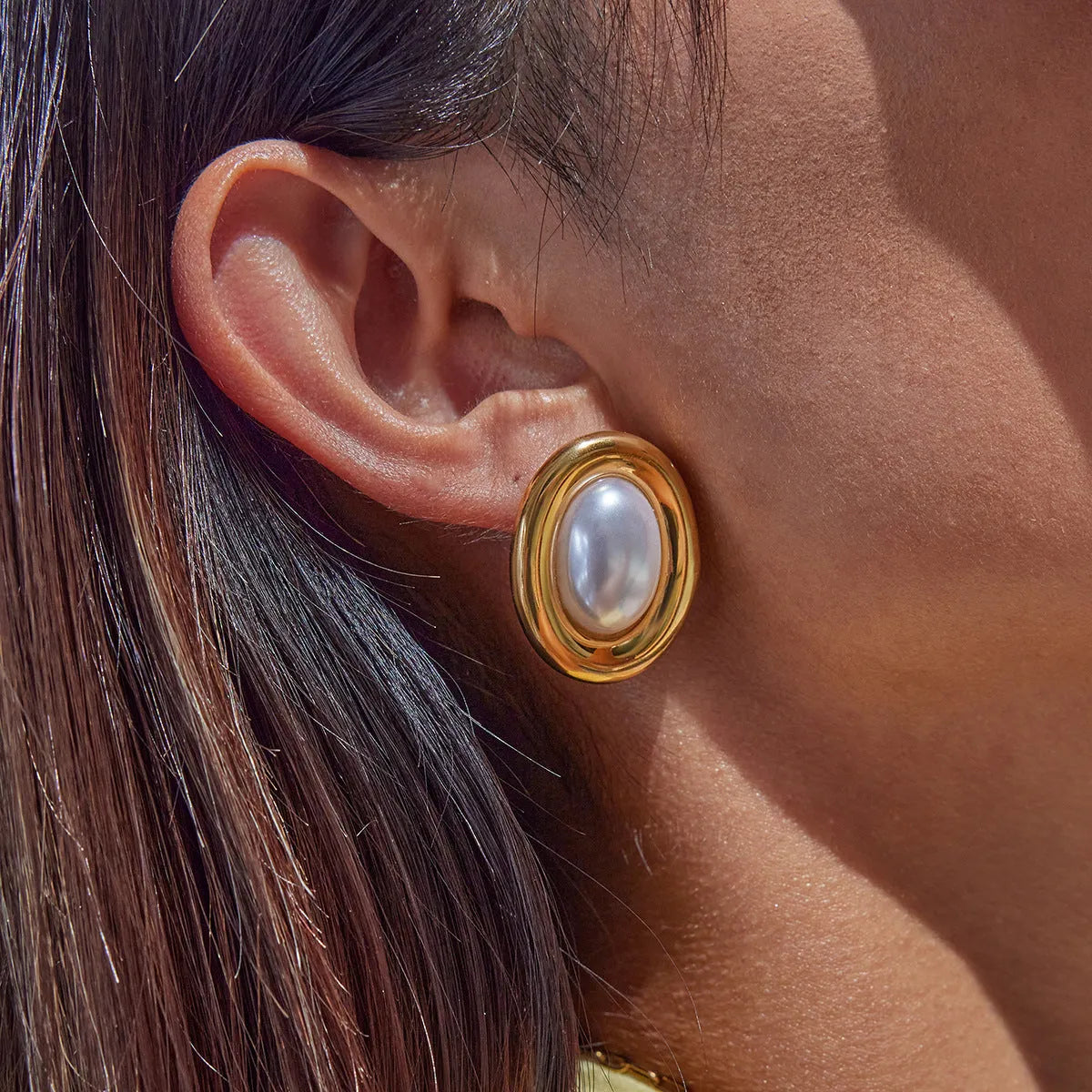 A pair of stainless steel stud earrings with a small vintage-style pearl drop and a non-fade electroplated finish.