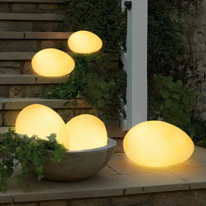 Outdoor pebble light in stone shape with IP65 waterproof rating, available in 26-48cm sizes for garden path, solar or rechargeable power options