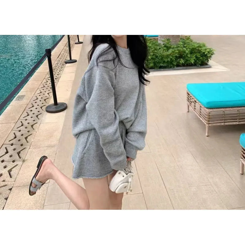 Woman wearing a loose grey long sleeve knitted sweater and matching wide leg shorts set.
