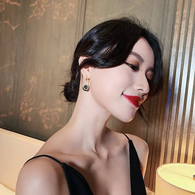 Black retro-style geometric alloy earrings with a round piece, shown from the side.