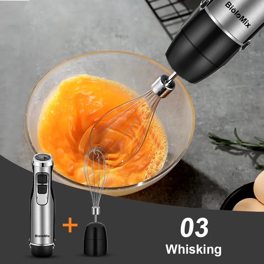 Silver and black Biolomix hand blender set with motor, stainless steel shaft, whisk, chopper bowl, and blending beaker on a kitchen counter.