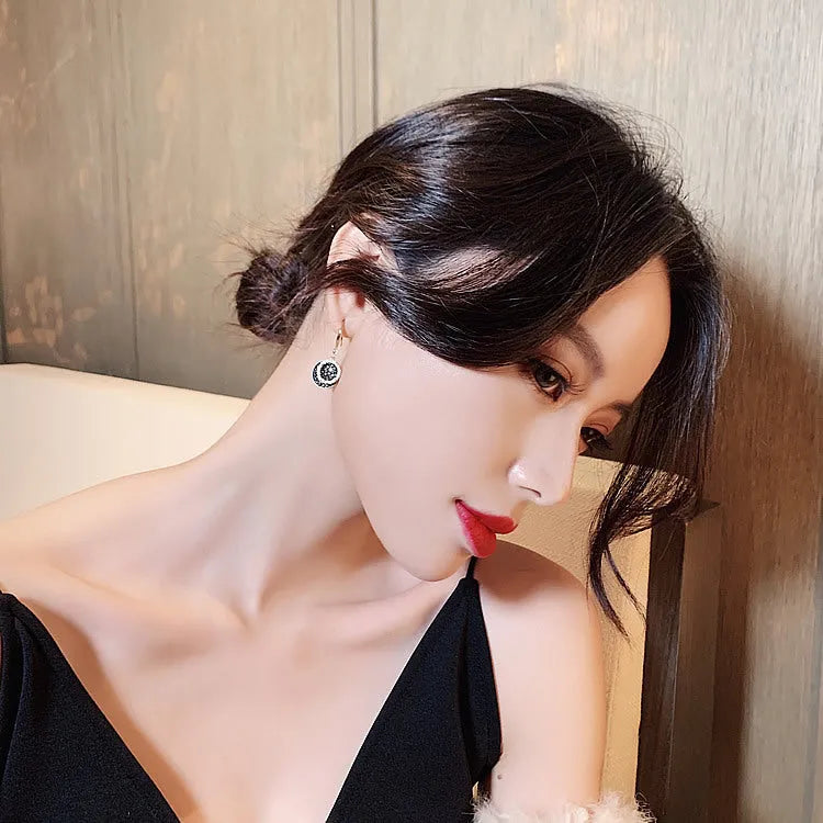 Black retro-style geometric alloy earrings with a round piece, shown from the side.