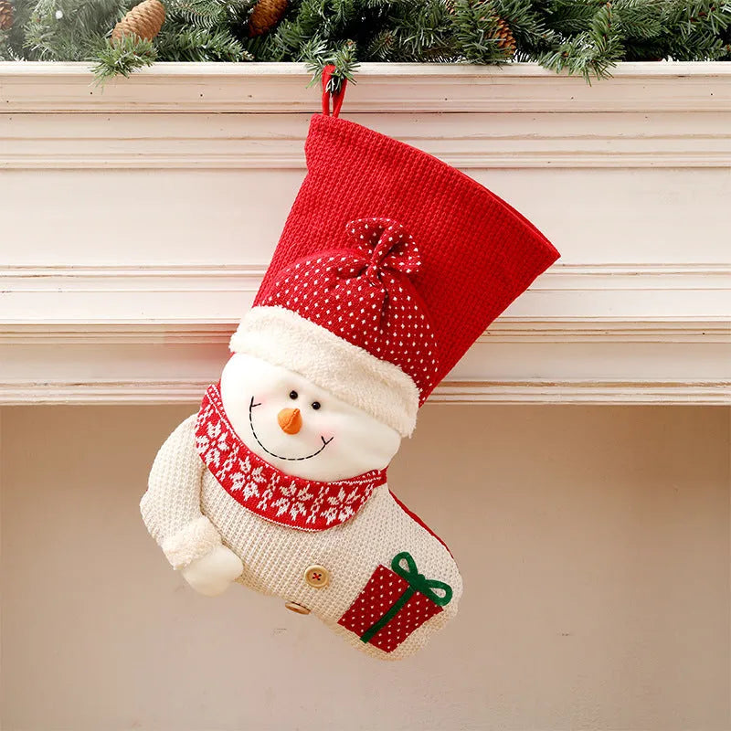 Large red and white knitted Christmas stocking with Santa Claus design hanging on a fireplace.