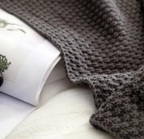 Nordic style fringed acrylic blanket in beige, measuring 130 by 170 centimetres, draped over a sofa.