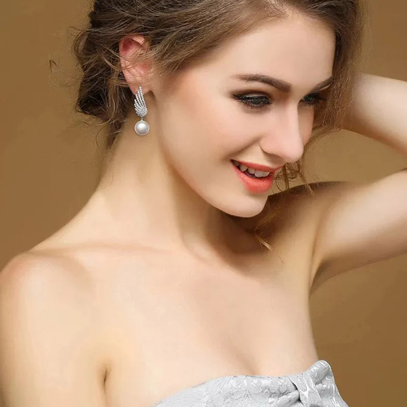 A pair of silver angel wing earrings with diamond treatment and gold-plated gemstone inlays on a platinum-colour finish.