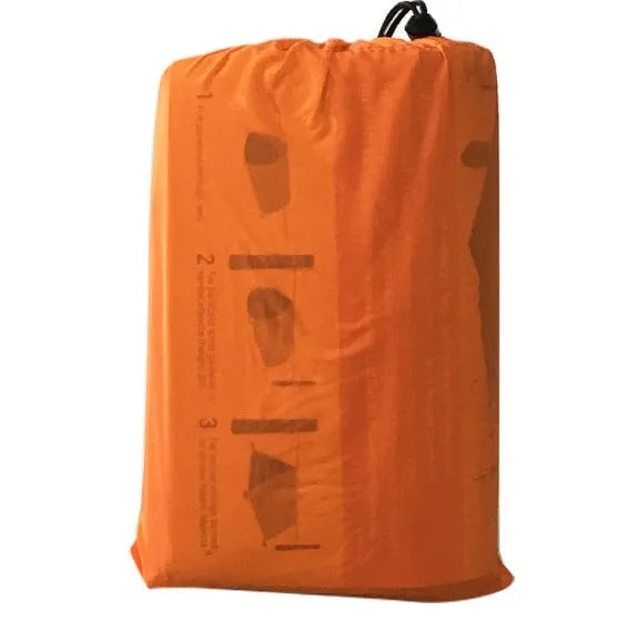 Orange PE aluminium film emergency sleeping bag folded and laid flat on outdoor ground