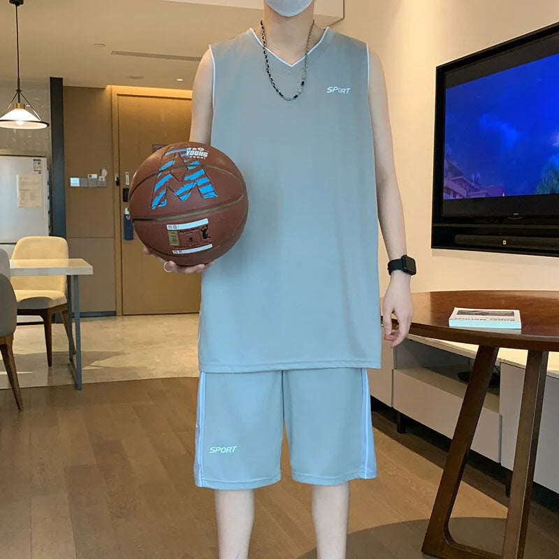 Man wearing a grey sleeveless polyester vest and matching shorts basketball sports set.