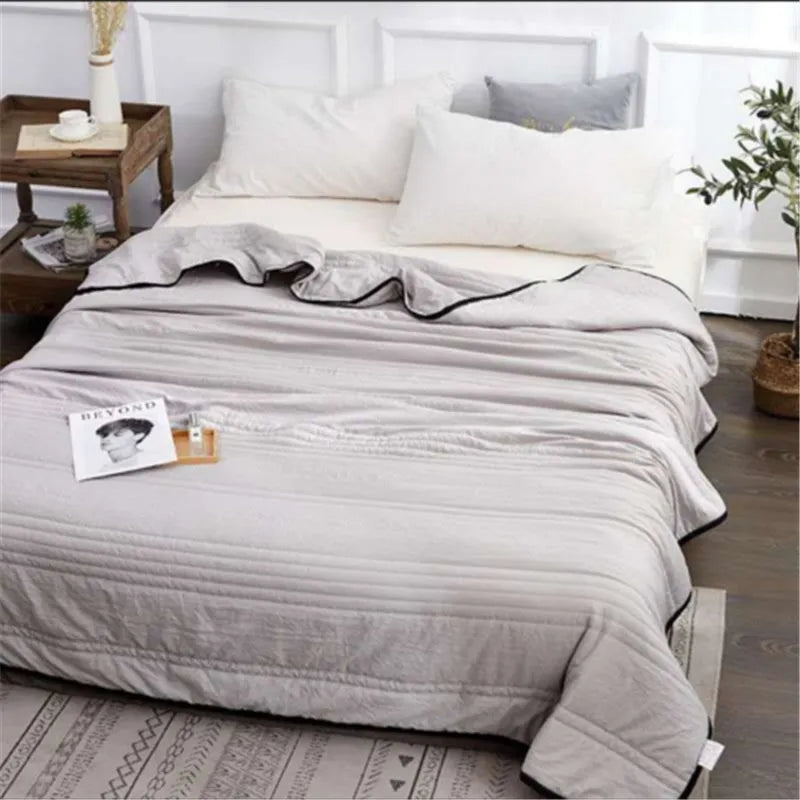Plain colour seersucker summer cooling quilt shown in light pink on a bed.