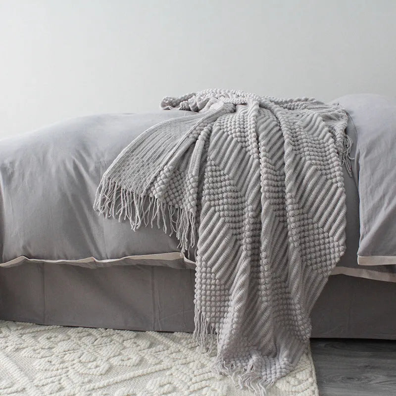 Small grey polyester nap blanket folded on a sofa, showing its 127x170cm size.