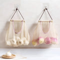 Beige plaid polyester mesh storage bag with cotton rope hanging loop on a white wall