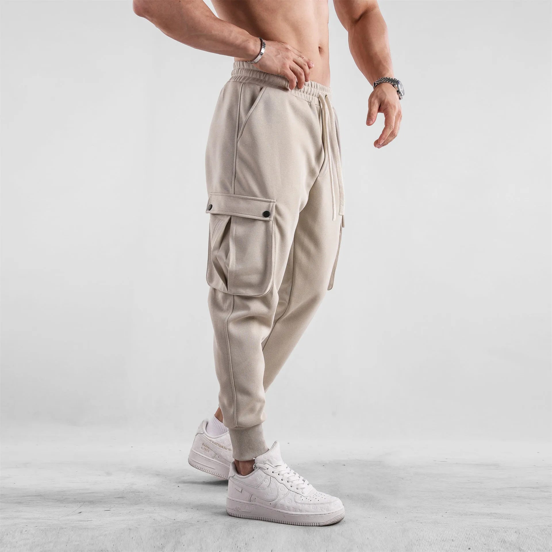 Man wearing loose light grey cotton sports trousers with ankle ties and multiple pockets.