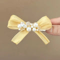 Yellow bow hair clip with rhinestone pearl accents and duckbill clip design