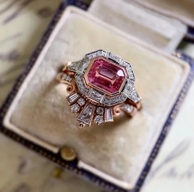 Rose gold coloured alloy women's ring with a geometric retro design and ruby-style details on a white background.