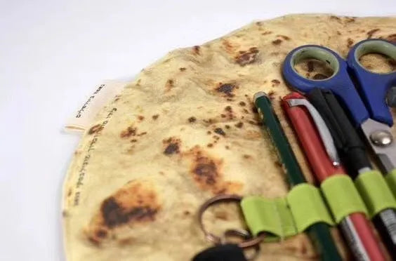 Fabric simulation burrito pencil case in clay oven rolls style, 22cm square, on a desk with pens inside