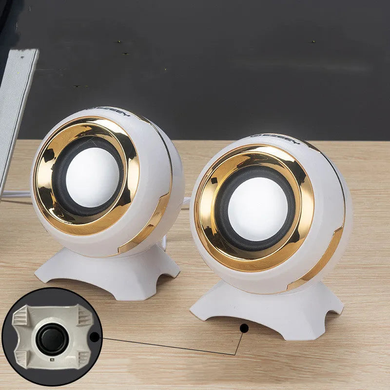 Compact black and gold USB-powered stereo computer speakers beside laptop
