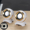 Compact black and gold USB-powered stereo computer speakers beside laptop