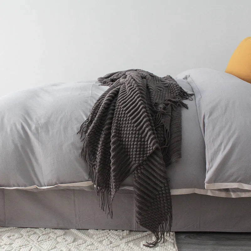 Small grey polyester nap blanket folded on a sofa, showing its 127x170cm size.