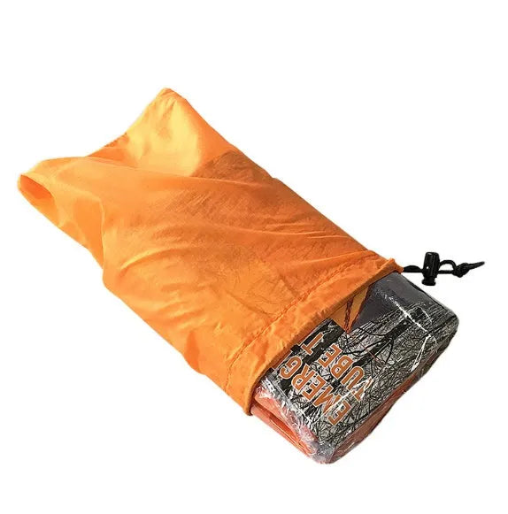 Orange PE aluminium film emergency sleeping bag folded and laid flat on outdoor ground