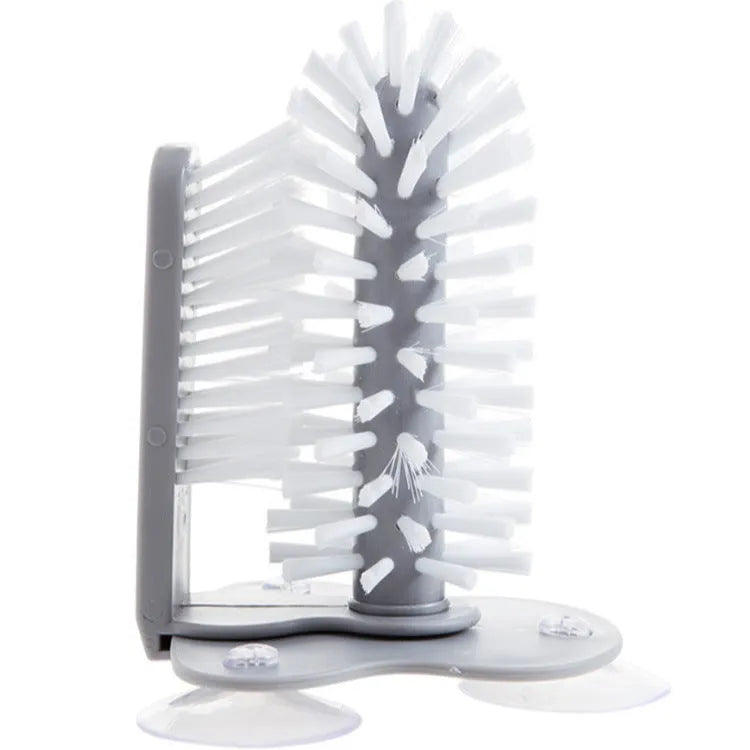 Grey 2-in-1 cup scrubber with double-sided bristles and three suction cups on a white surface
