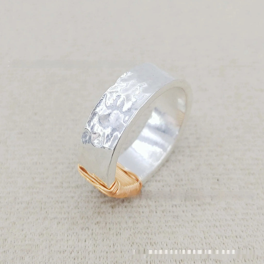 Copper wide face geometric ring bracelet in silver gold coil colour on a plain background.