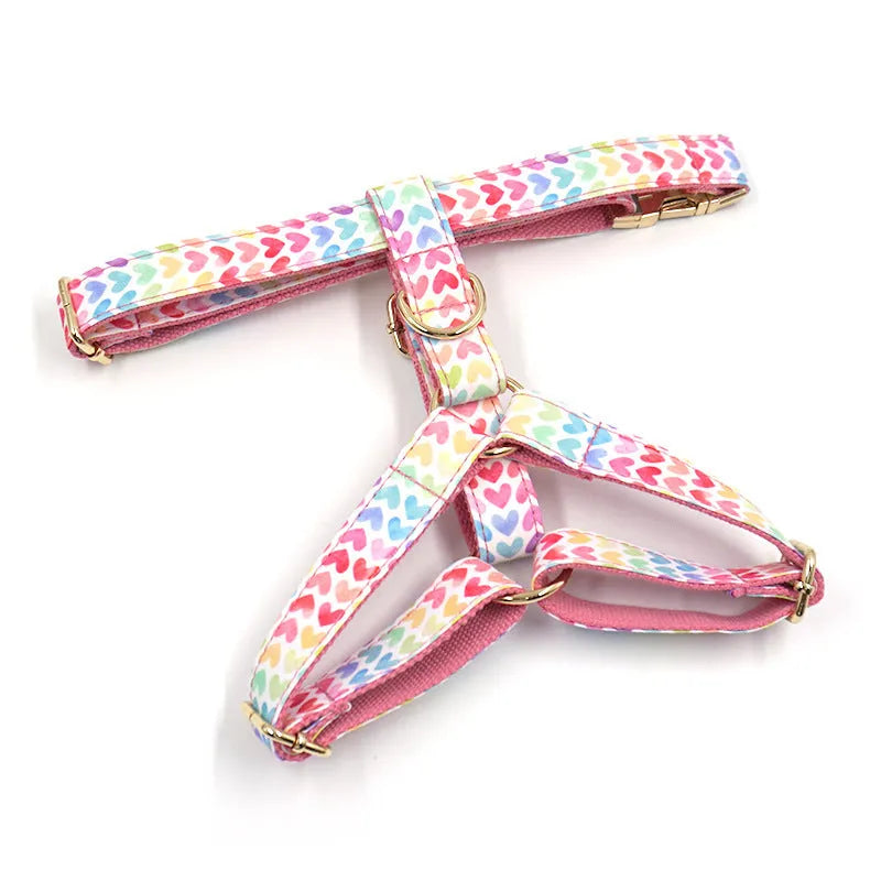 Pink dog harness with a gold buckle and a colourful heart-shaped stone on the chest strap.
