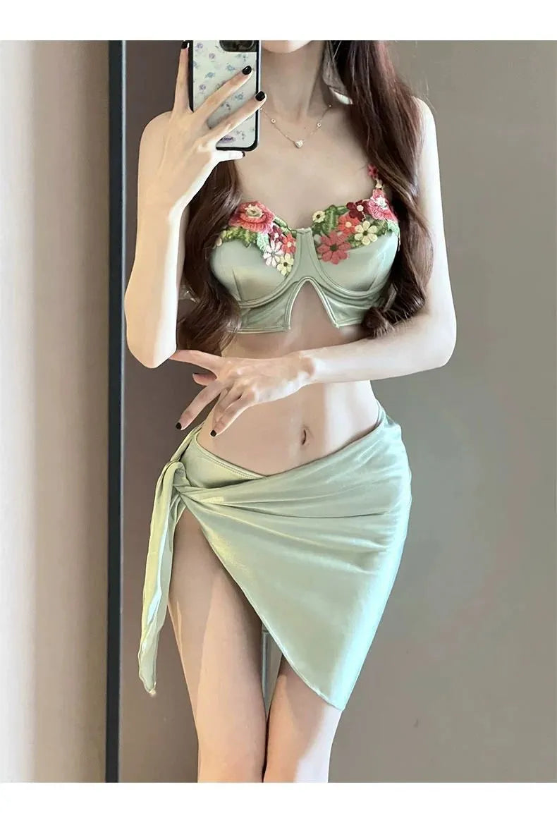 Green women's three-piece bikini swimsuit set with triangle top, briefs, and a short skirt on a mannequin.