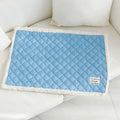 Blue quilted cloth pet blanket for cats lying flat, showing its rectangular shape and textured surface.