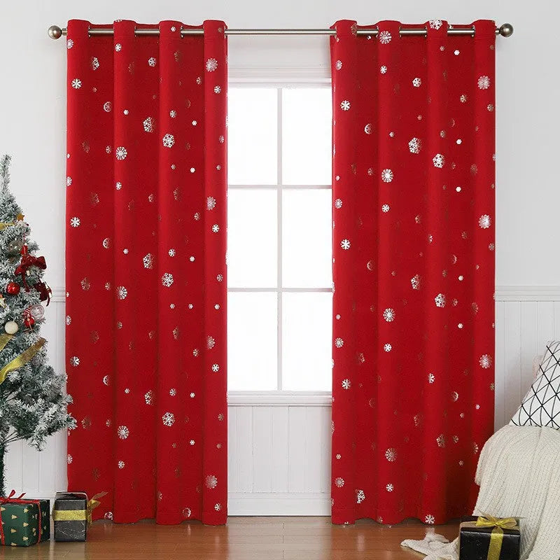 Red snowflake pattern shade cloth curtain with iron hoops hanging on a rod against a window.