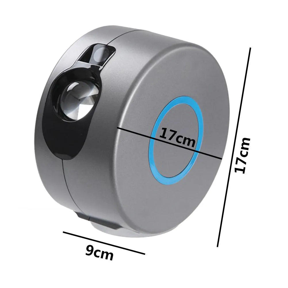 Grey starry sky projection lamp with remote control on a table, projecting light onto a ceiling.