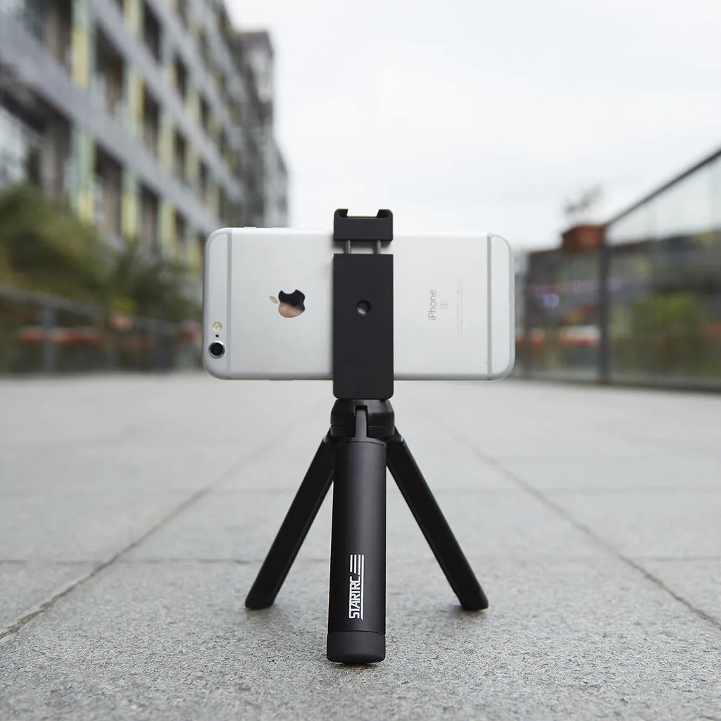 Silver aluminium alloy handheld phone mounting bracket for table top tripods, shown next to an iPhone.