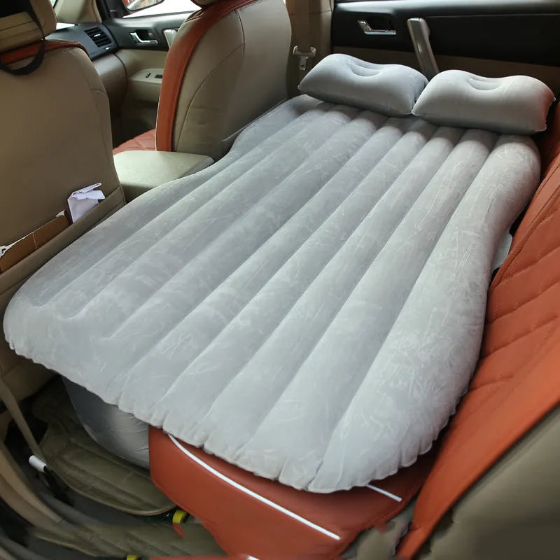 Universal inflatable car bed with flocked surface, shown with two pillows inside a vehicle.