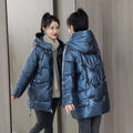 Green loose-fit hooded women's winter jacket on a hanger, showing long sleeves.