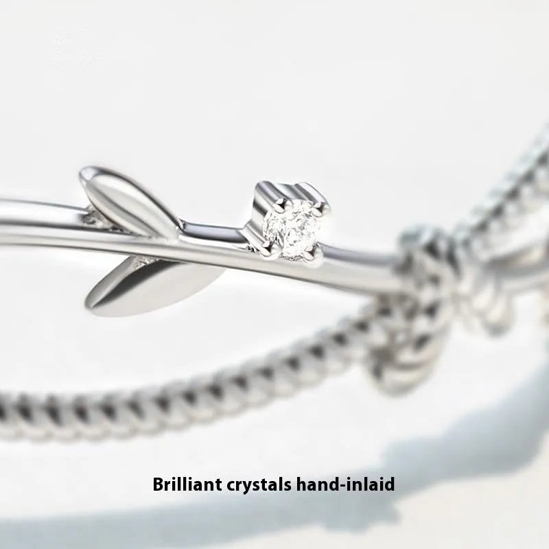 Close-up of a white gold coloured twisted branch sprout design bracelet on a wrist.
