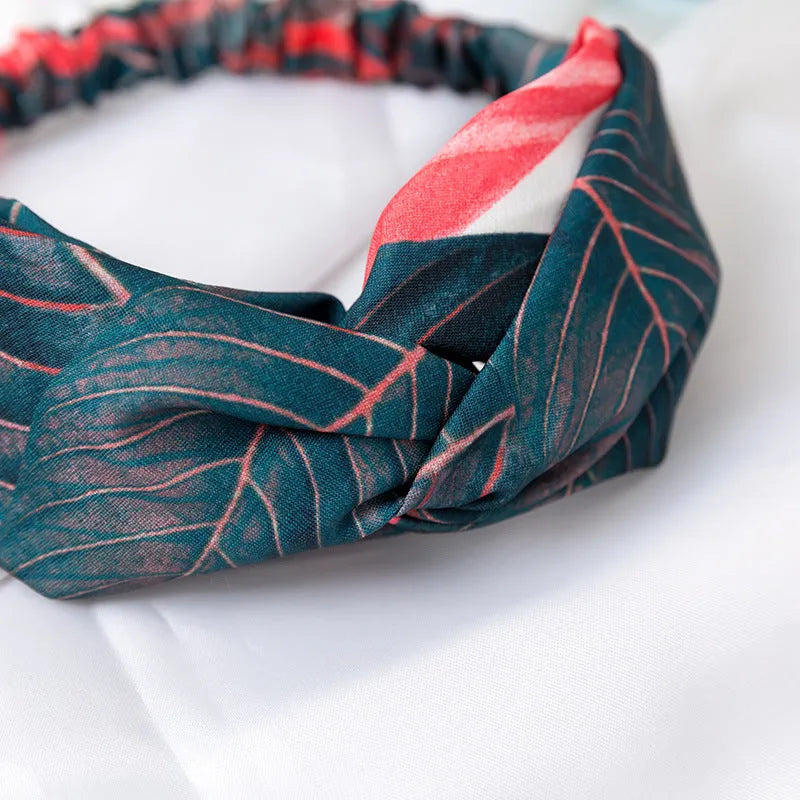Red cloth headband with banana leaf pattern, showing wide band and elastic back.