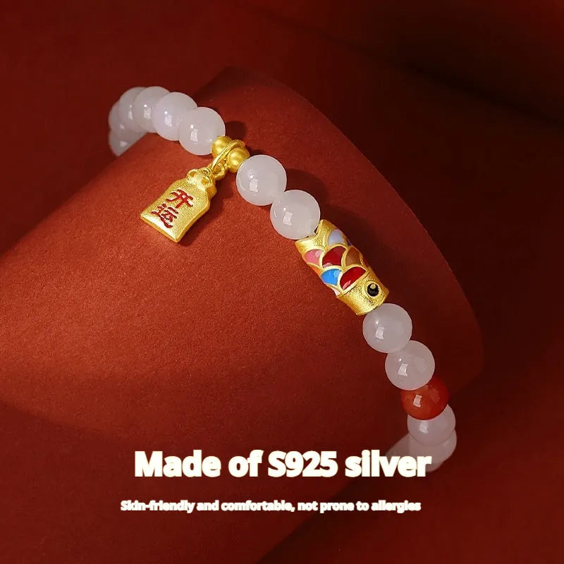 Close-up of a women's sterling silver bracelet with a koi fish cold enamel design and a natural Hetian jade component.