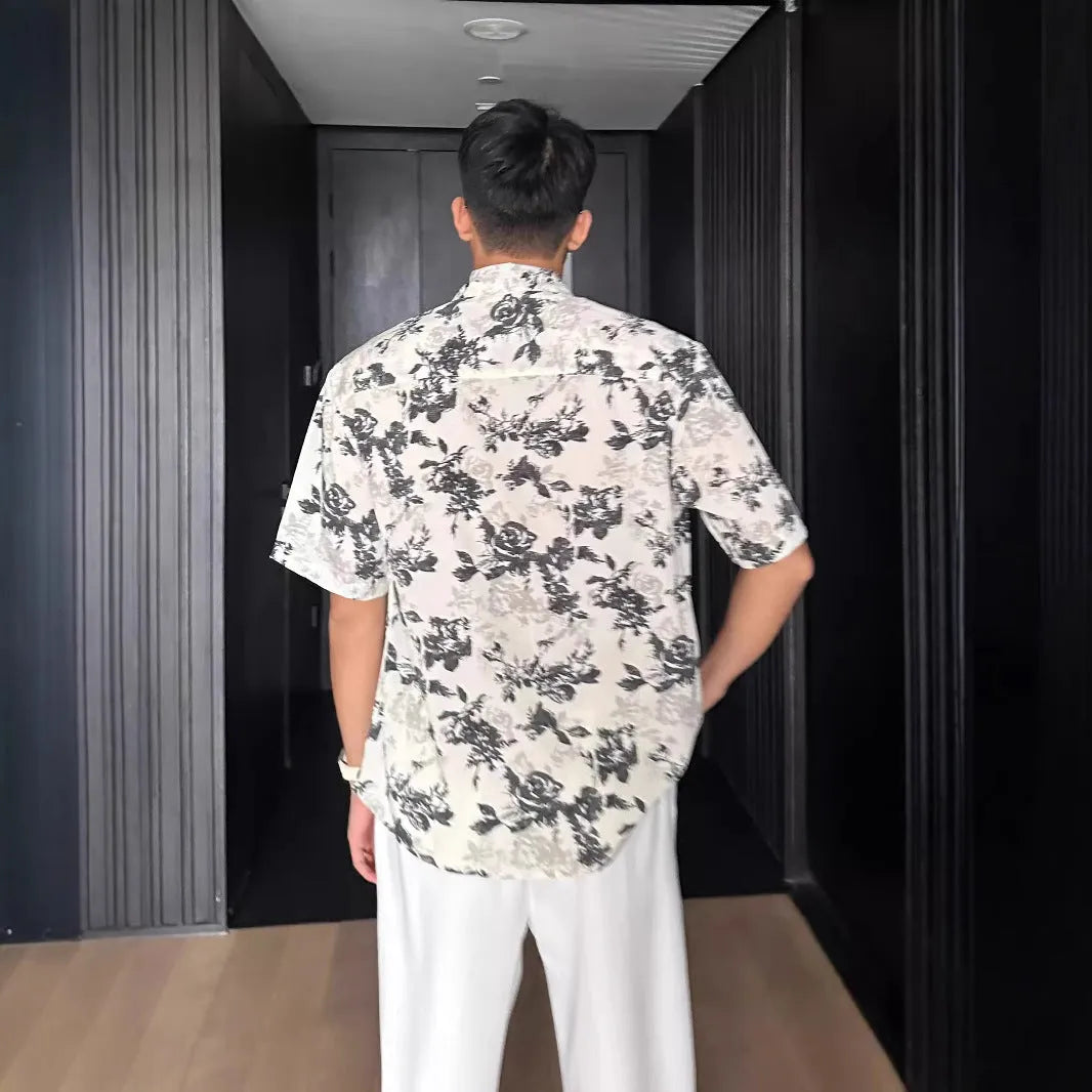 Black and white loose-fit floral printed short sleeve casual shirt on a hanger.